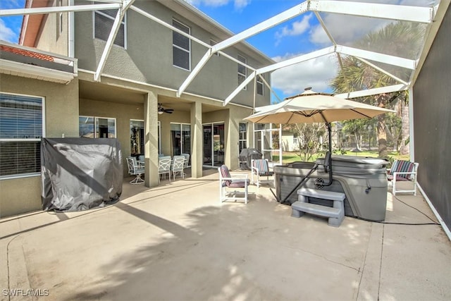 view of patio with a hot tub, ceiling fan, and glass enclosure