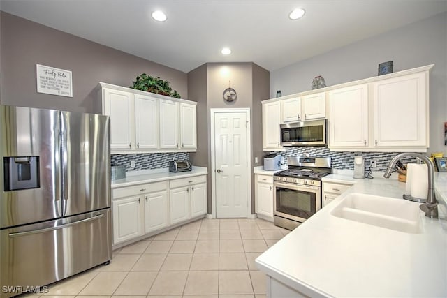 kitchen with sink, stainless steel appliances, white cabinets, light tile patterned flooring, and decorative backsplash