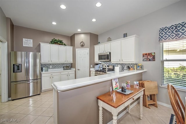 kitchen with stainless steel appliances, light tile patterned floors, white cabinets, and kitchen peninsula