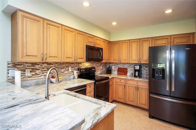 kitchen featuring sink, decorative backsplash, light stone counters, and black appliances