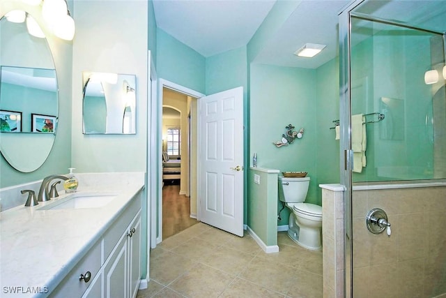 bathroom featuring a shower with door, vanity, tile patterned flooring, and toilet