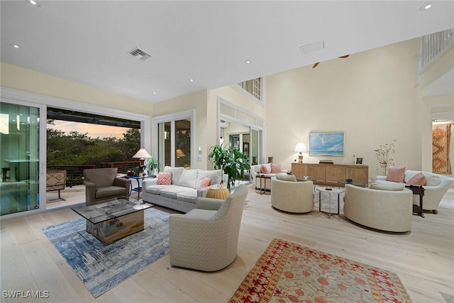 living room with a towering ceiling and light hardwood / wood-style flooring