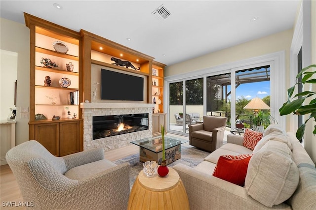 living room with built in shelves and light hardwood / wood-style floors