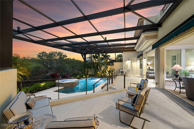 pool at dusk featuring an in ground hot tub, glass enclosure, and a patio