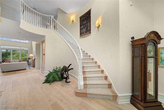 stairs featuring hardwood / wood-style flooring and a towering ceiling