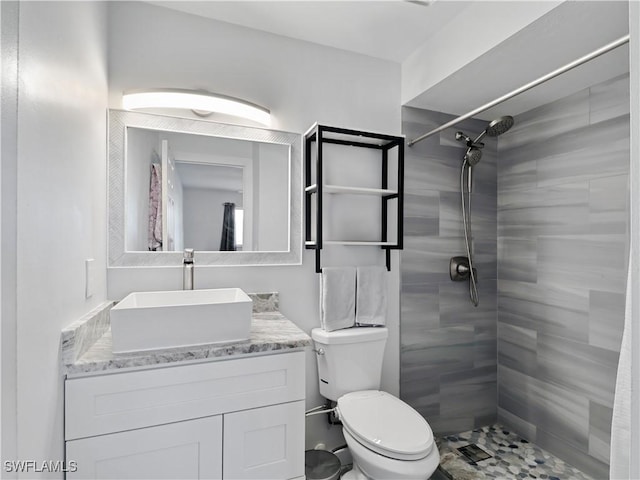 bathroom with vanity, toilet, and a tile shower