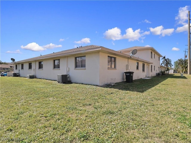 back of house with central AC unit and a lawn