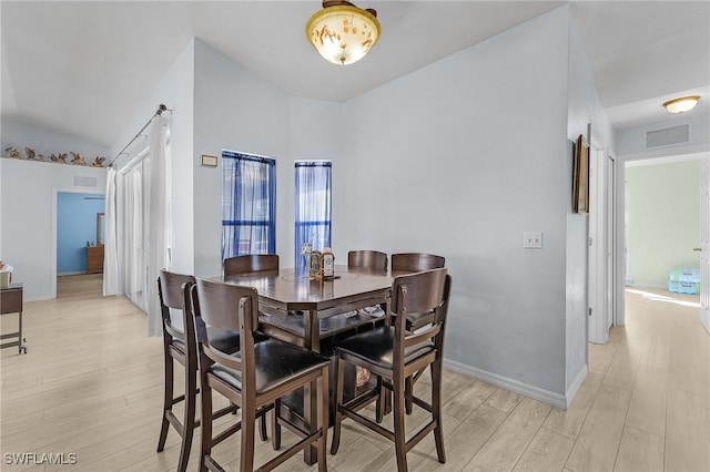 dining area with vaulted ceiling and light hardwood / wood-style floors