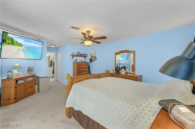 bedroom with ceiling fan, light colored carpet, and connected bathroom