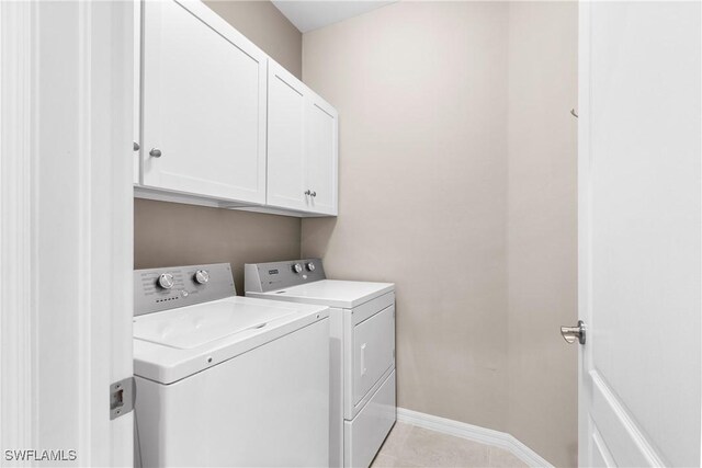 laundry room featuring light tile patterned floors, washer and clothes dryer, cabinet space, and baseboards