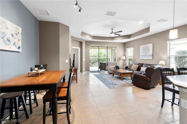 living area with light tile patterned floors, visible vents, and a raised ceiling