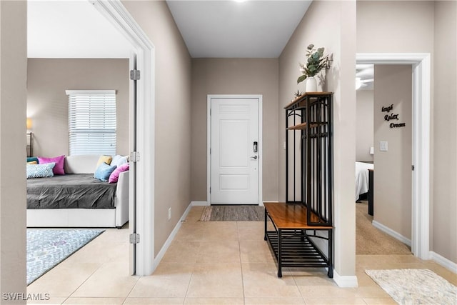 interior space with ceiling fan, baseboards, and light tile patterned flooring