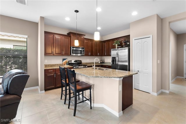 kitchen featuring stainless steel appliances, a sink, visible vents, light stone countertops, and decorative light fixtures