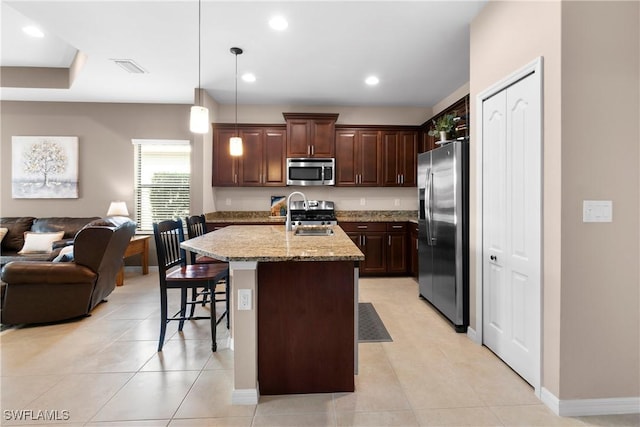 kitchen with light stone counters, a kitchen breakfast bar, open floor plan, stainless steel appliances, and a sink