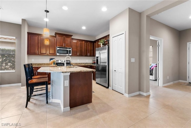 kitchen with stainless steel appliances, recessed lighting, a sink, an island with sink, and light stone countertops