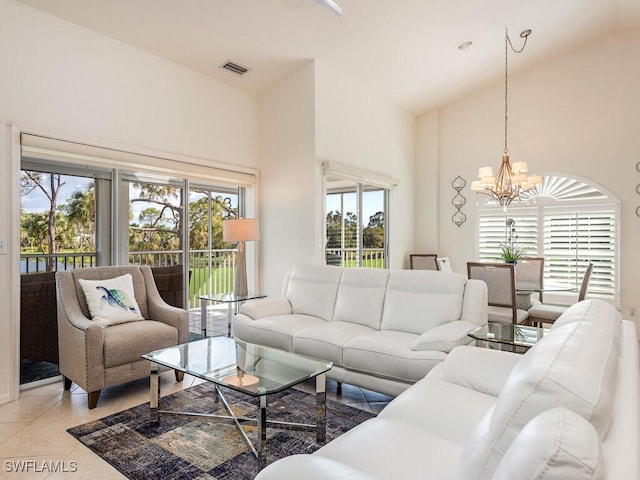 living room featuring light tile patterned flooring, a healthy amount of sunlight, a notable chandelier, and a towering ceiling