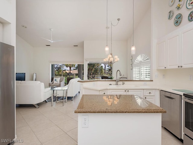 kitchen featuring light tile patterned flooring, white cabinets, hanging light fixtures, a center island, and plenty of natural light