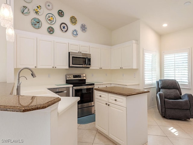 kitchen featuring sink, white cabinetry, hanging light fixtures, stainless steel appliances, and kitchen peninsula