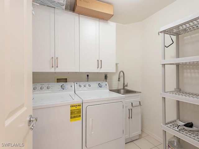 washroom with sink, light tile patterned floors, washing machine and dryer, and cabinets