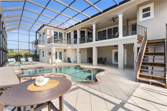 rear view of property featuring a patio area, ceiling fan, and glass enclosure