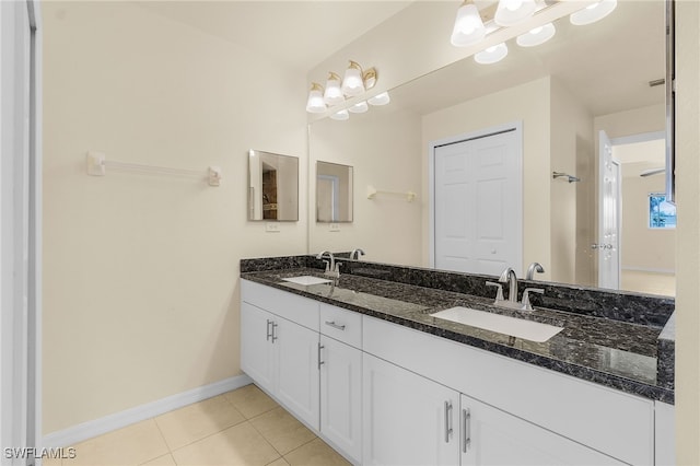 bathroom with baseboards, double vanity, a sink, and tile patterned floors