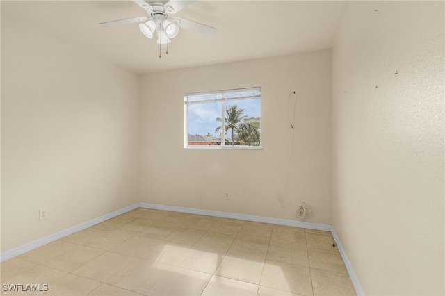 tiled empty room with ceiling fan and baseboards