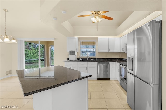 kitchen with light tile patterned flooring, stainless steel appliances, a kitchen island, white cabinets, and decorative light fixtures