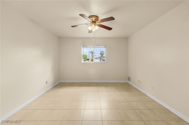 empty room featuring ceiling fan, light tile patterned flooring, and baseboards