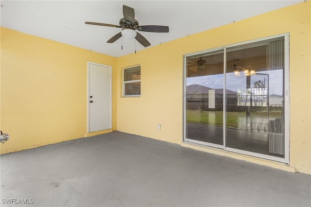 unfurnished room featuring ceiling fan with notable chandelier and concrete floors