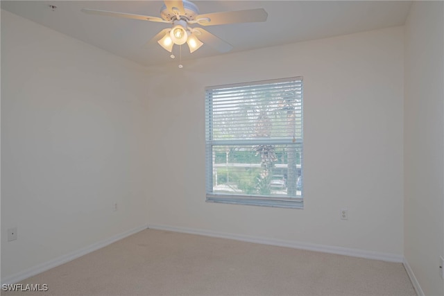 carpeted spare room featuring ceiling fan and baseboards