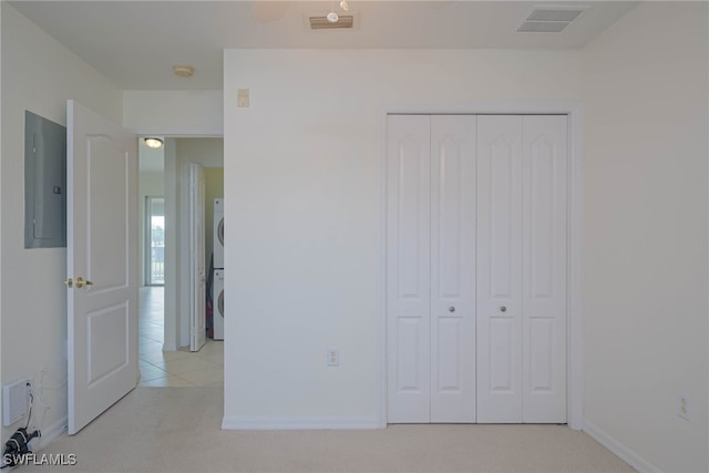 unfurnished bedroom with stacked washer / drying machine, a closet, electric panel, and visible vents