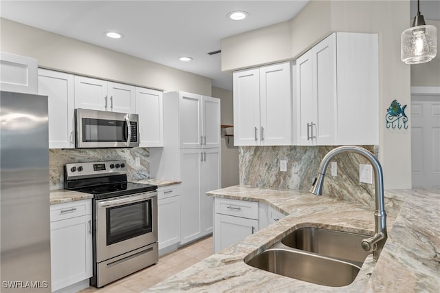 kitchen featuring light stone countertops, white cabinetry, stainless steel appliances, and a sink