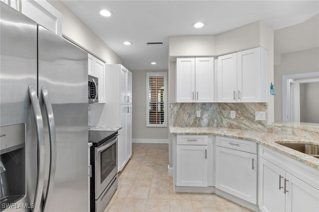 kitchen featuring light stone countertops, appliances with stainless steel finishes, white cabinets, and backsplash