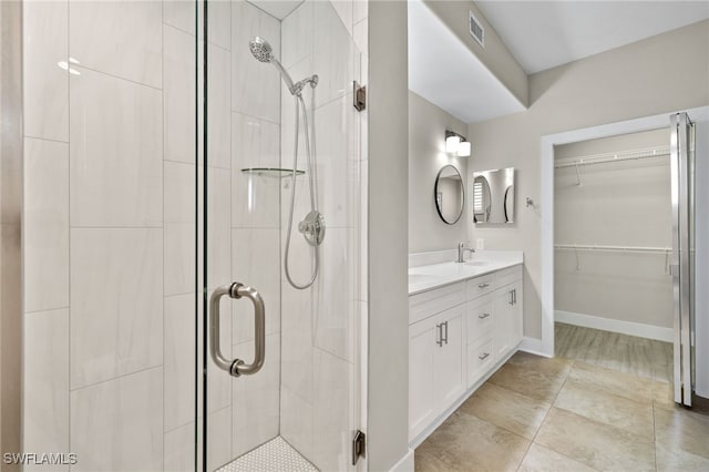 full bath featuring a sink, visible vents, a spacious closet, double vanity, and a stall shower