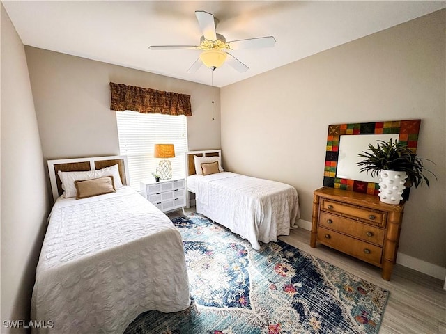 bedroom featuring wood finished floors, a ceiling fan, and baseboards