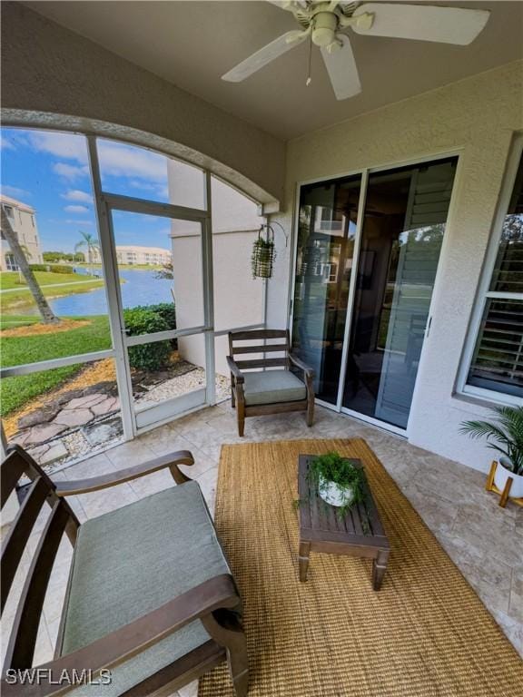 sunroom with a water view and ceiling fan