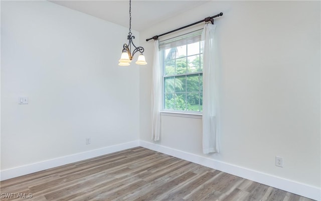 empty room featuring hardwood / wood-style floors and a notable chandelier