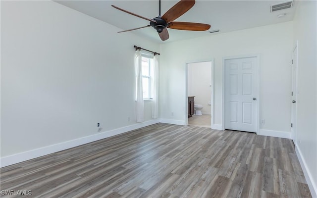 unfurnished bedroom with ceiling fan, ensuite bathroom, and light wood-type flooring