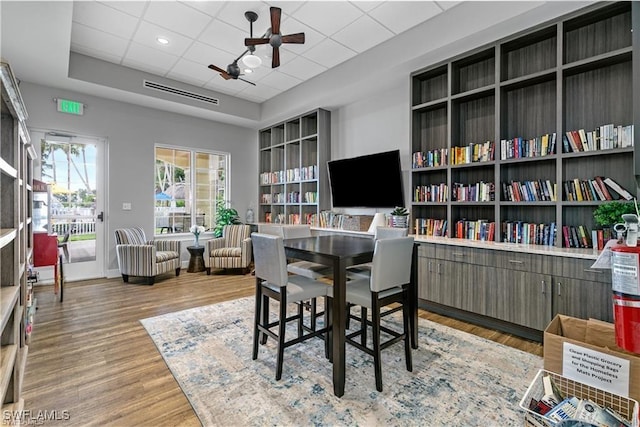 office space with a tray ceiling, wood-type flooring, ceiling fan, and a paneled ceiling