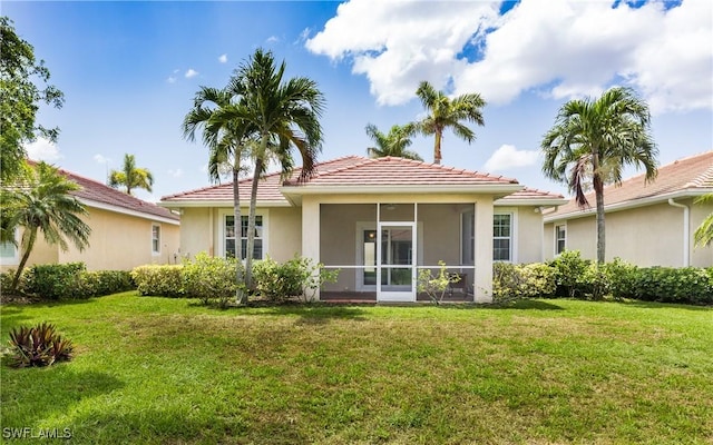 rear view of house featuring a sunroom and a yard