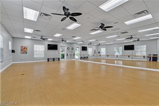 workout area with a drop ceiling and light wood-type flooring