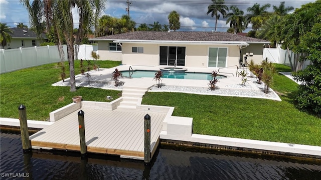 back of house with a water view, a swimming pool with hot tub, a yard, and a patio area