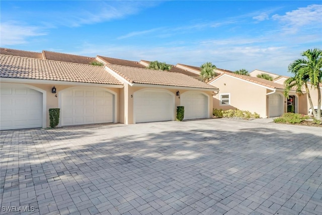 view of front of property featuring stucco siding, a tiled roof, and driveway