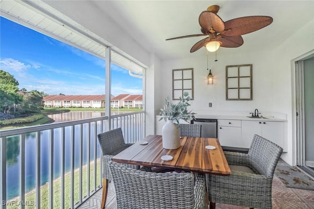 sunroom / solarium with a residential view, a water view, ceiling fan, and a sink