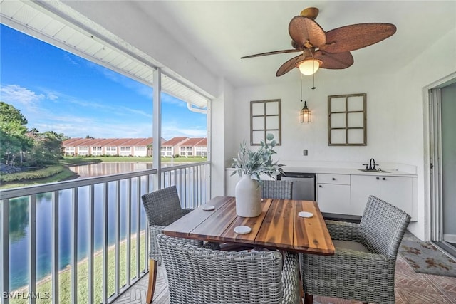 sunroom featuring a water view, a sink, a residential view, and a ceiling fan