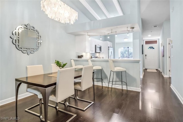 dining space featuring an inviting chandelier, dark wood-type flooring, baseboards, and track lighting