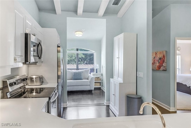 kitchen featuring visible vents, beam ceiling, appliances with stainless steel finishes, white cabinets, and light countertops