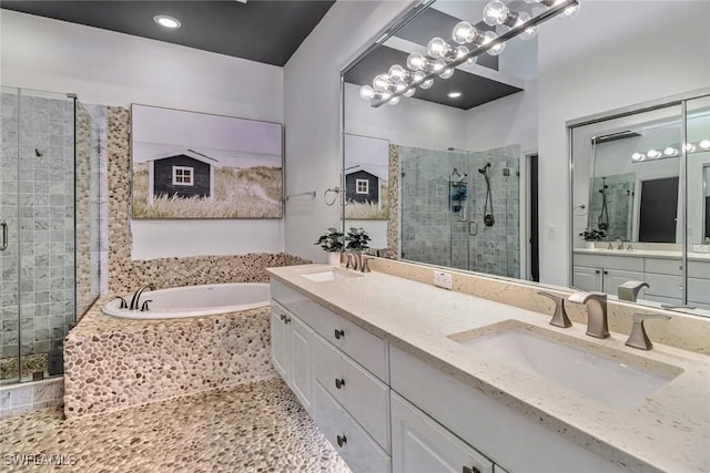 bathroom with a garden tub, double vanity, a stall shower, and a sink