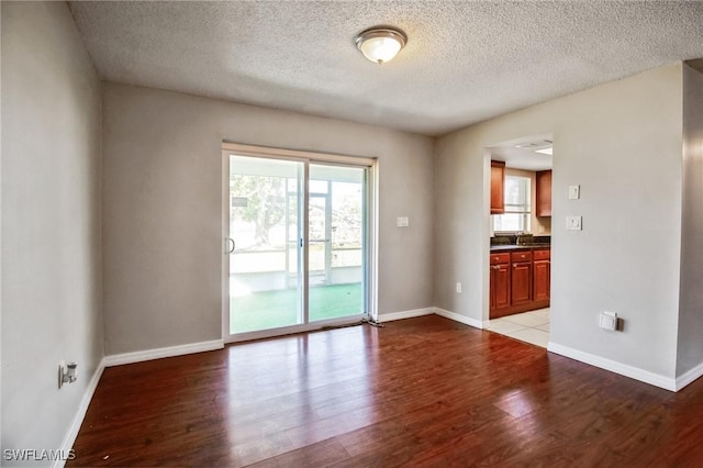 spare room featuring sink, light hardwood / wood-style floors, and a textured ceiling