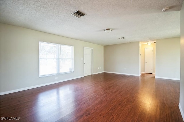 unfurnished room with dark wood-type flooring and a textured ceiling